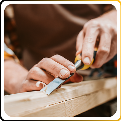 A carpenter working on some timber with a chisel