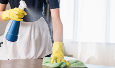 a chamber maid cleaning a hotel room table in a hotel