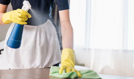 a chamber maid cleaning a hotel room table in a hotel